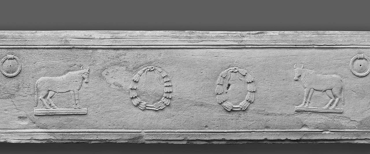 A broken limestone fragment of a carved sarcophagus.